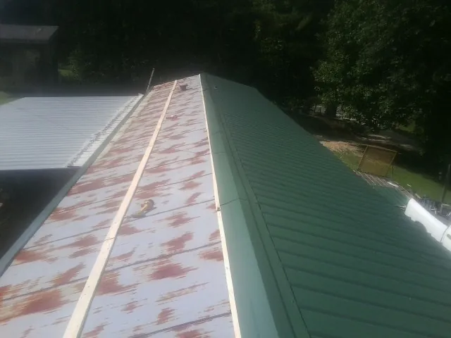 Old rusted panels beside newly installed green metal roofing — Wind Damage Roof Repair by Roofing Brothers in Milwaukee