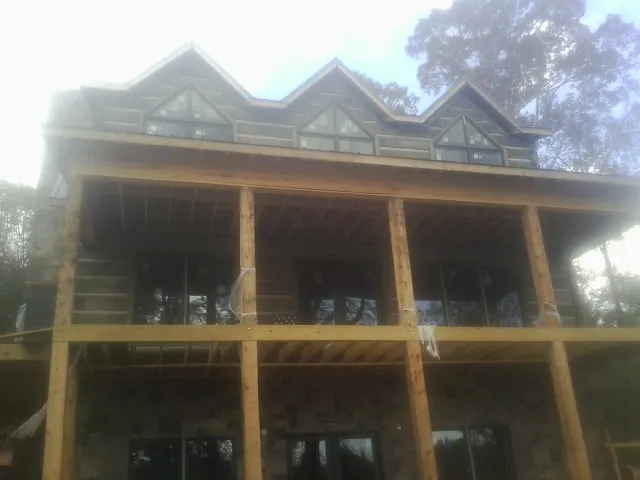 Dormers and porch framing on a large log home under construction — Roof Coating work by our crew in Milwaukee