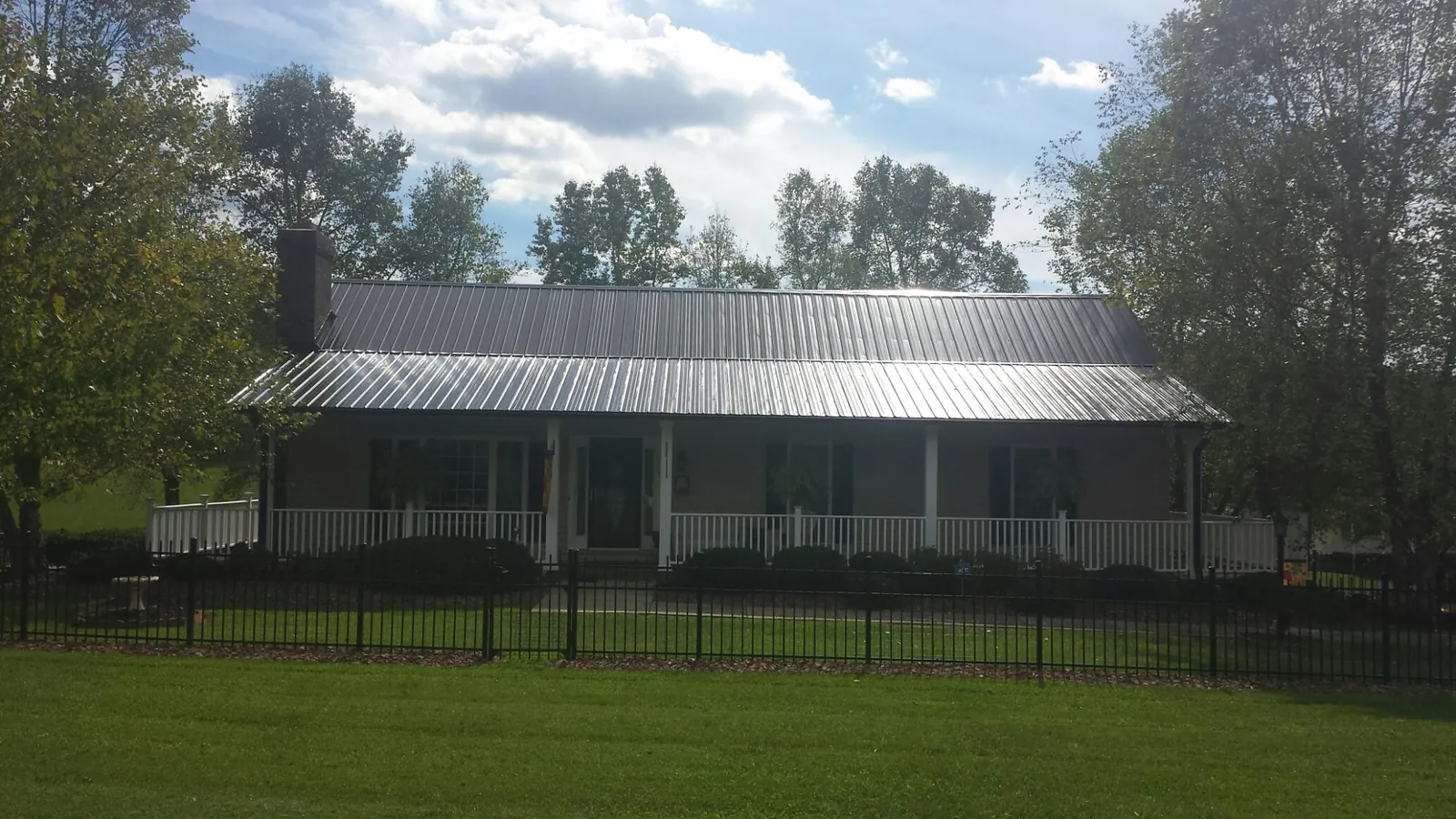 Gray metal roof on a brick ranch with a full width front porch — Gutter Guard Installation work by our crew in Milwaukee