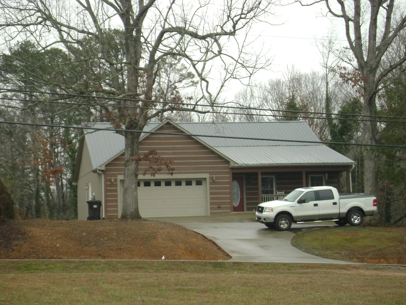 Gray metal roof on a log sided house with an attached two car garage in Milwaukee