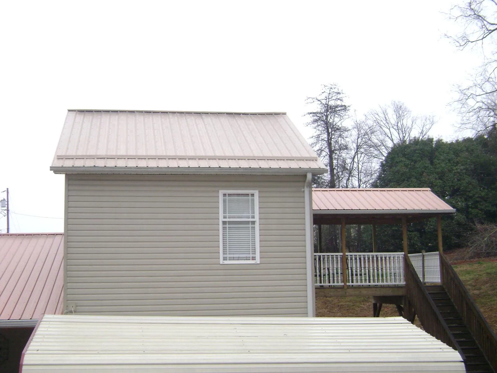 Tan metal roofs on a two story addition and attached porch, from a Roof Replacement job in Milwaukee