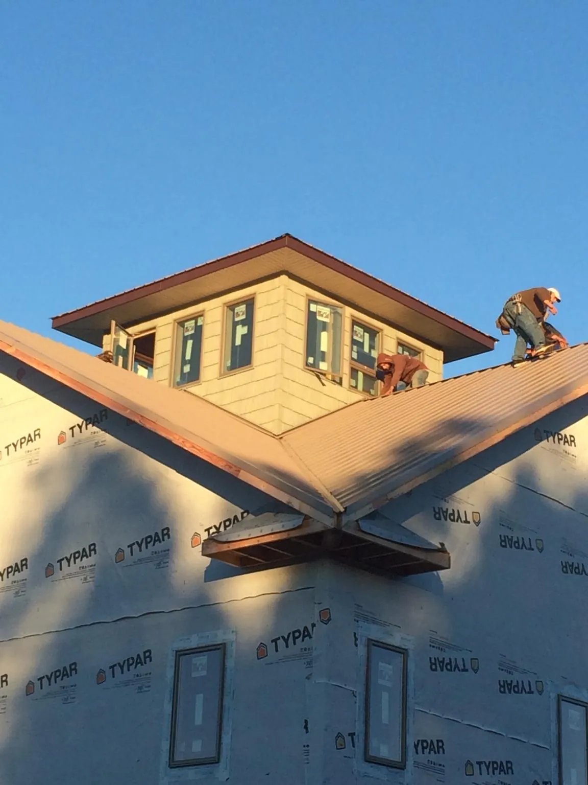 Roofers working around a rooftop cupola on a new metal roof at sunset — Roof Waterproofing in Milwaukee by Roofing Brothers